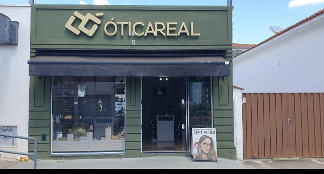 Fachada verde da Ótica Real com letreiro dourado e vitrines de vidro